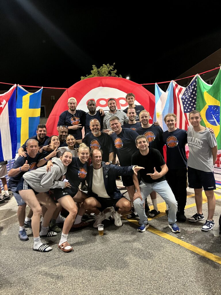 nternational basketball coaches together at an Always Basketball camp in Italy with flags from countries around the world